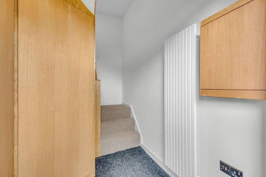 a hallway with a staircase with a wooden door at Pass the Keys Larkey View a Tranquil Space for Two in Chartham