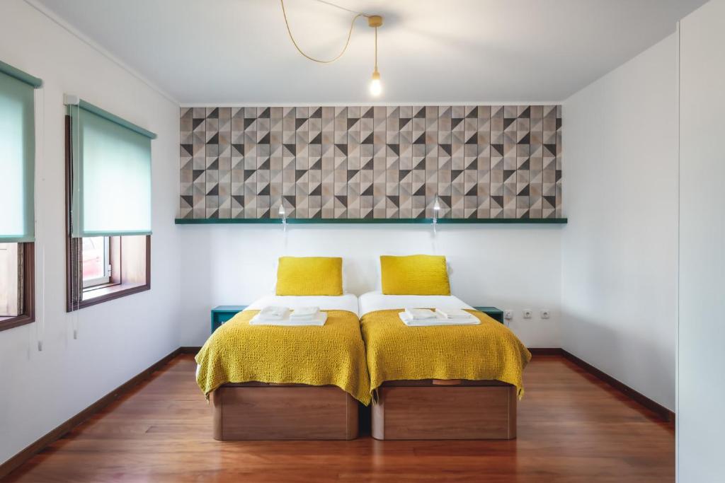 a bedroom with a bed with yellow blankets and yellow pillows at BeSmart Residence by Home Sweet Home Aveiro in Aveiro