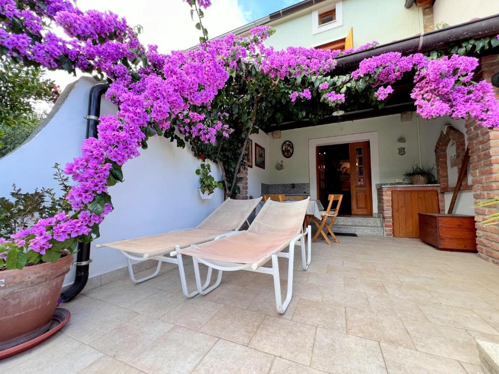 a patio with purple flowers and a table and chairs at Casa Bella Holiday Home Rab in Rab