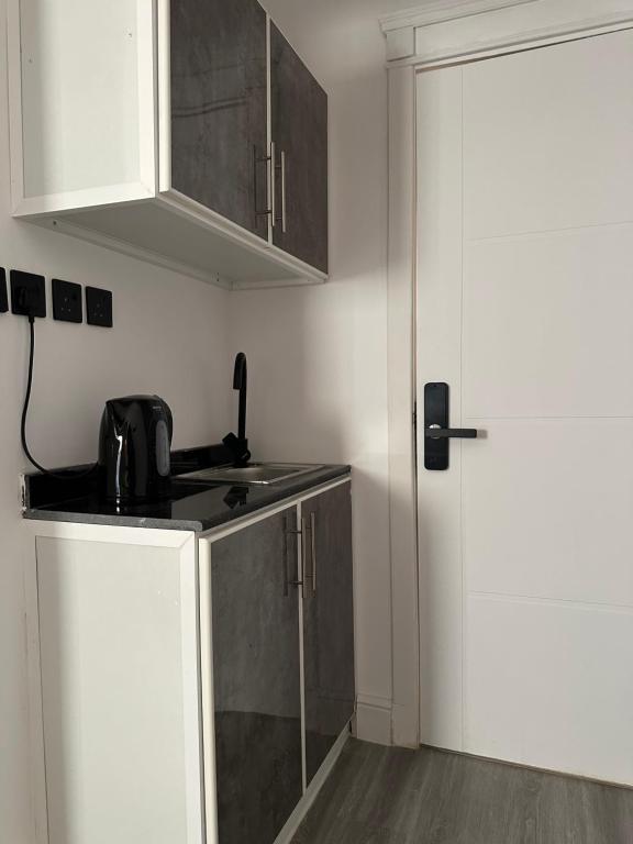 eine Küche mit weißen Schränken und einer Spüle und einer Tür in der Unterkunft استديو شمال الرياض in Riad