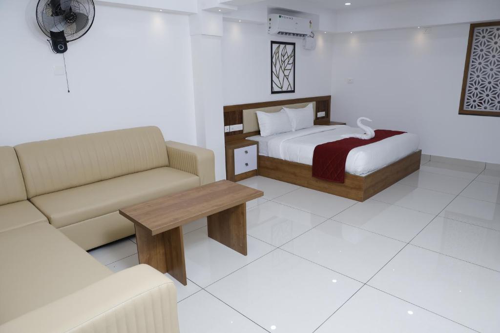 Un dormitorio con una cama, un sofá y una mesa. en Coral Inn Residency, en Kattappana