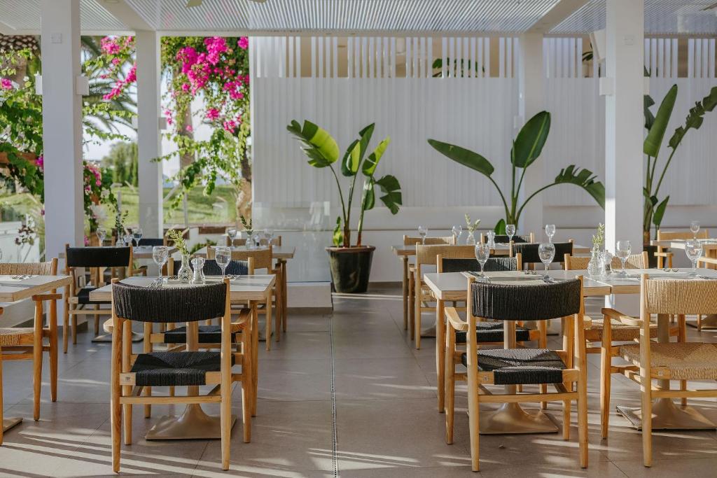 a restaurant with tables and chairs and plants at Nissi Beach Resort in Ayia Napa