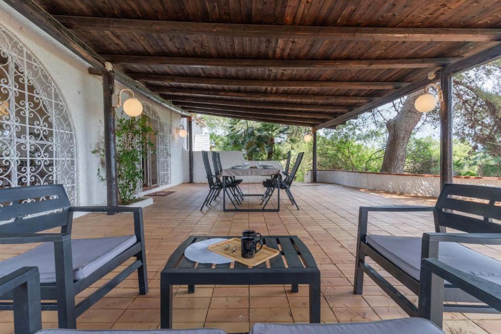 a patio with a table and chairs and a wooden ceiling at Villa Laura by Wonderful Italy in Alghero