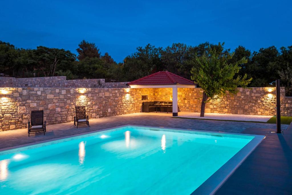 una piscina in un cortile posteriore di notte di Holiday Villa Effort in Skradin - Šibenik a Vačani