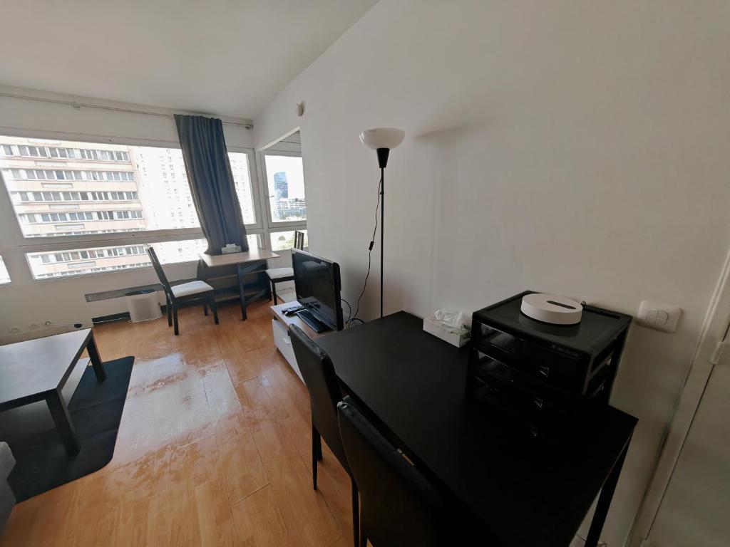 - un salon avec un bureau, une table et des chaises dans l'établissement Appartement lumineux proche de la ligne 14, à Paris