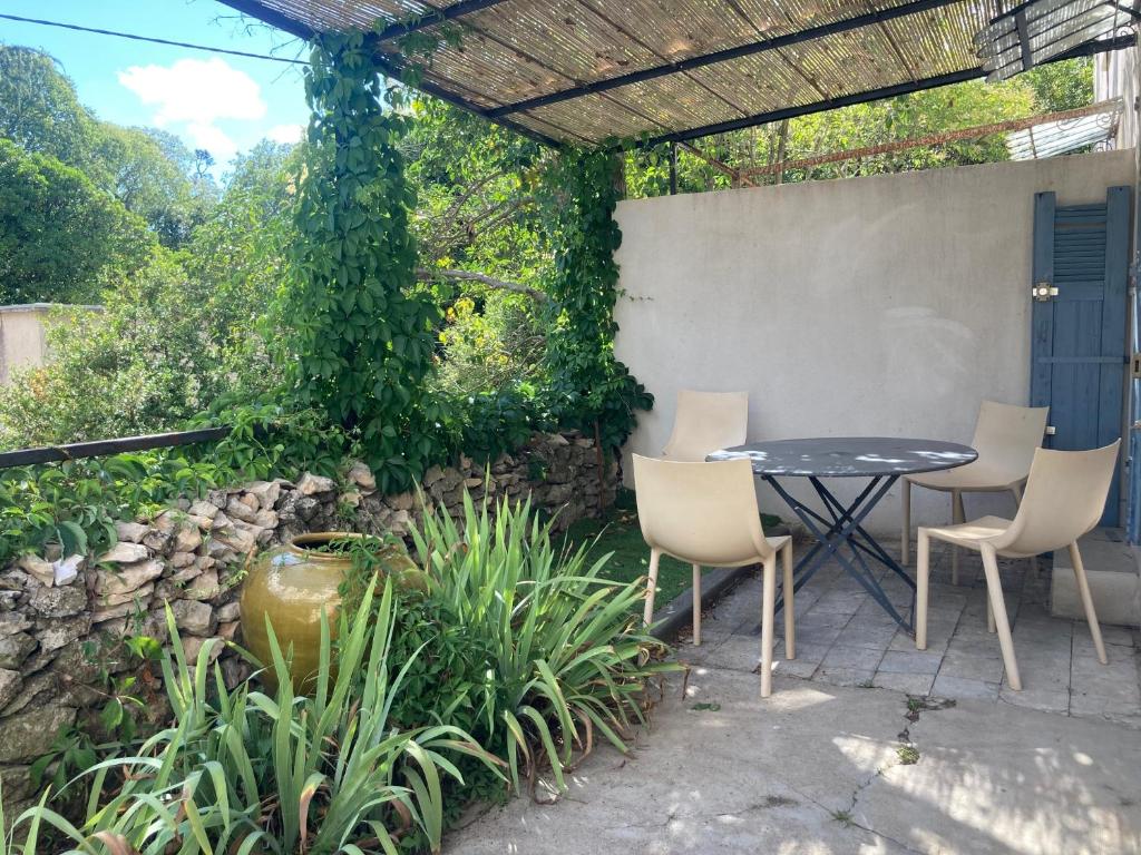 d'une terrasse avec une table, des chaises et un mur. dans l'établissement Le mazet des 3 piliers, à Nîmes
