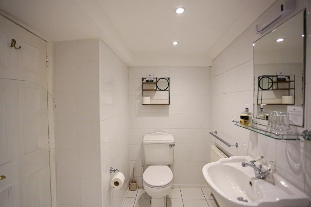a white bathroom with a toilet and a sink at The Wellington Hotel in Ventnor