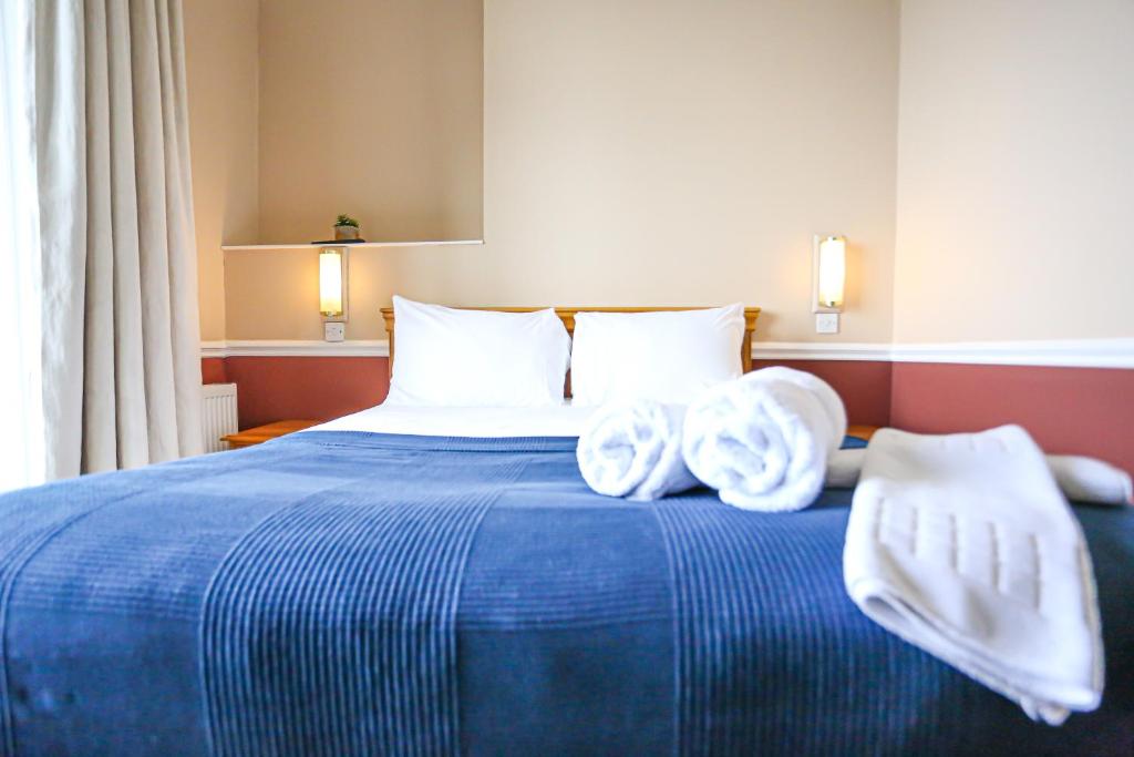 a bedroom with a blue bed with towels on it at The Wellington Hotel in Ventnor