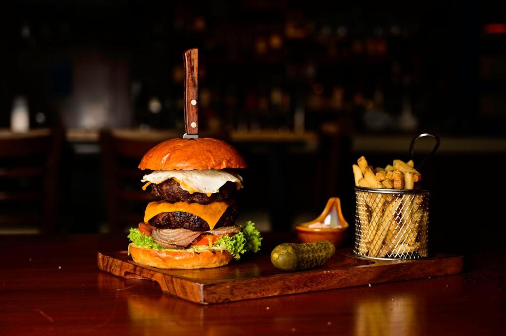 a large hamburger on a cutting board with a drink at Novotel Fujairah in Fujairah