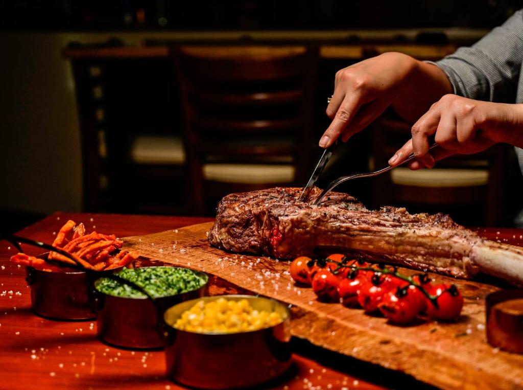 a person cutting up a piece of meat on a cutting board at Novotel Fujairah in Fujairah