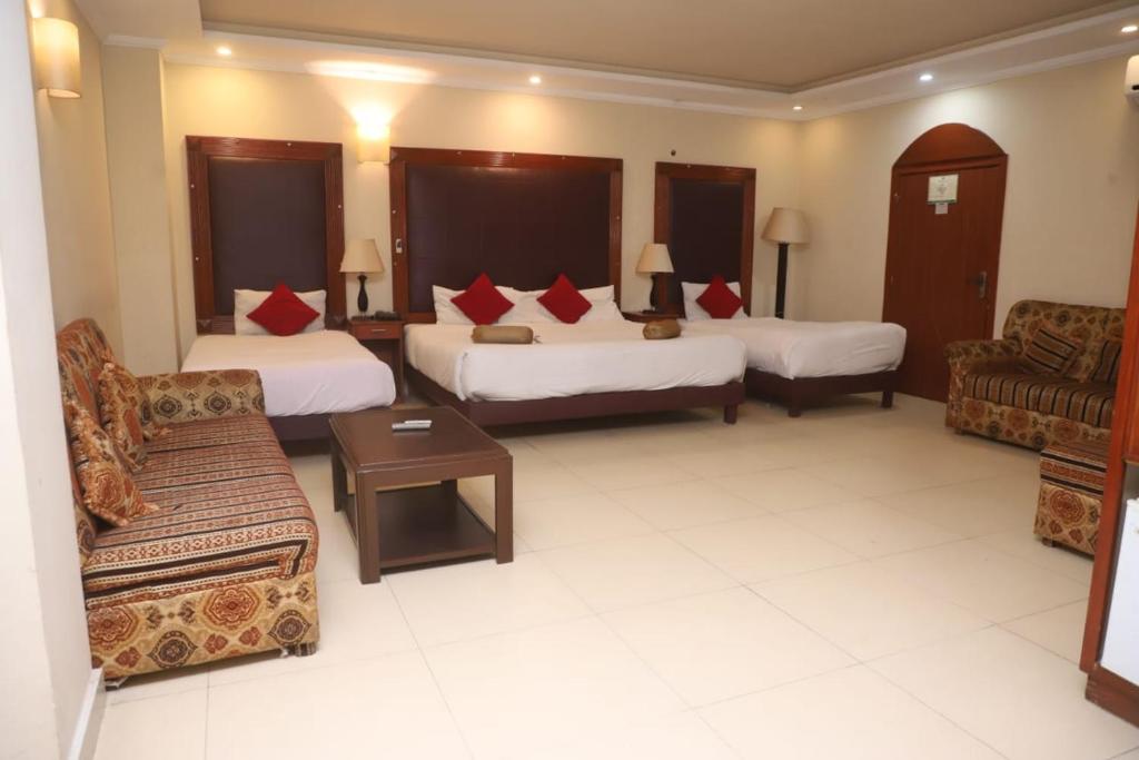 a hotel room with two beds and a couch at PAK Heritage Hotel in Lahore