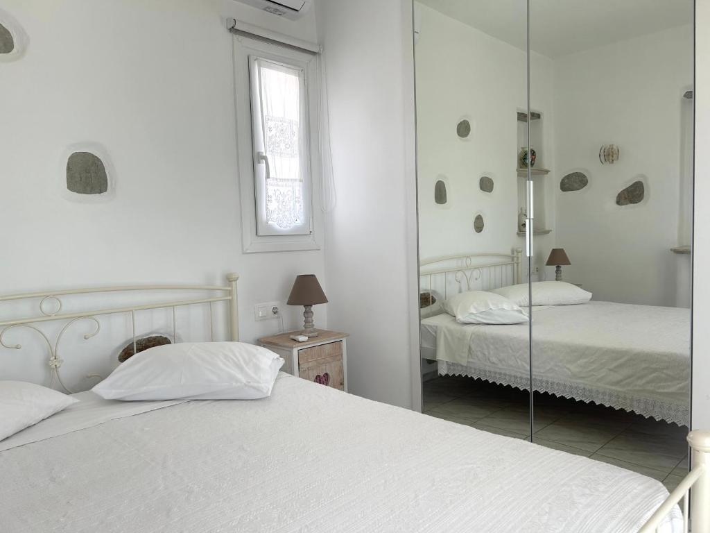 a white bedroom with two beds and a mirror at Antiparos Diamond in Antiparos Town