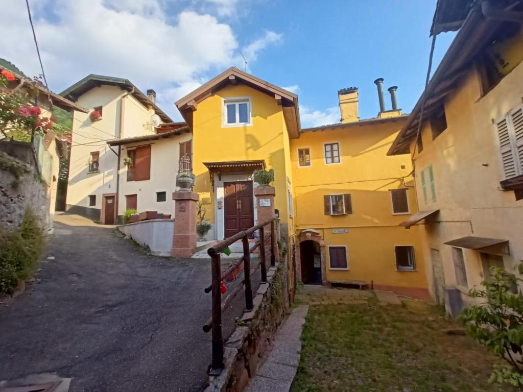 a yellow house on a street with a fence at Foresteria Lombarda B & B Ca' Pelitti in Ganna