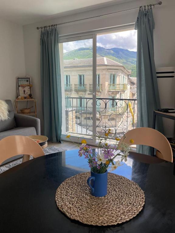 un salon avec une table avec un vase de fleurs dans l'établissement Un amour de Luchon, avec vue sur les Pyrénées, à Luchon
