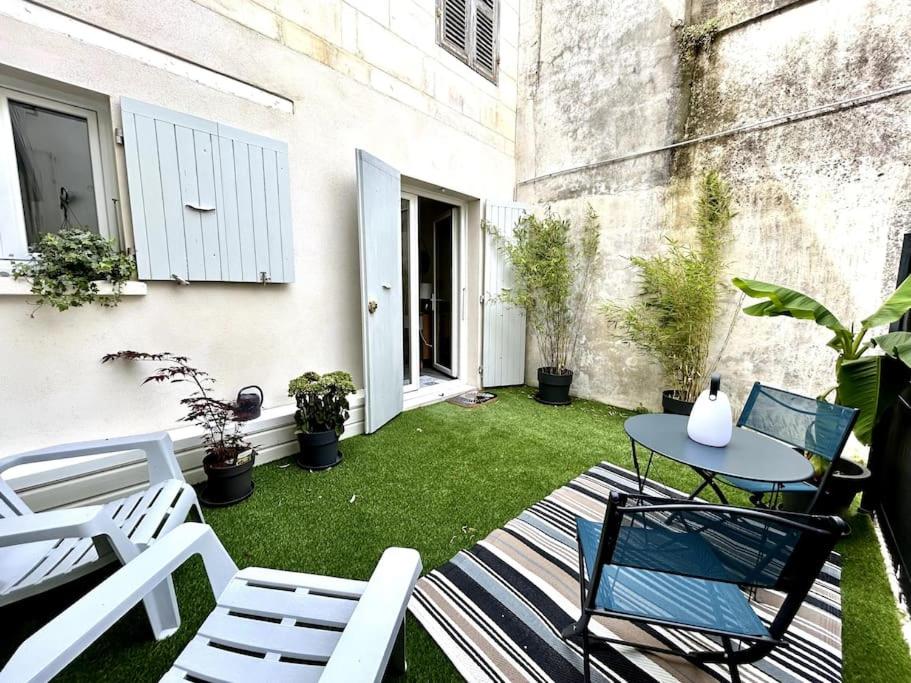 un petit patio avec des chaises et une table sur une pelouse dans l'établissement Côté Cour - Appartement en plein centre-ville & proche des thermes, à Rochefort