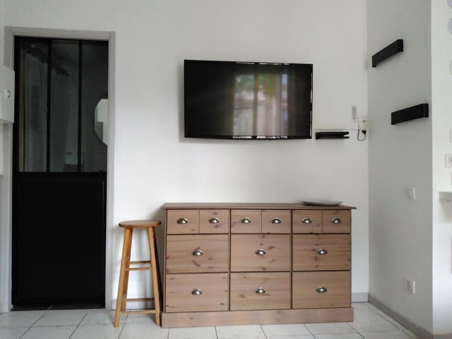 - une commode en bois avec une télévision murale dans l'établissement Studio tout confort centre-ville, à Tarbes