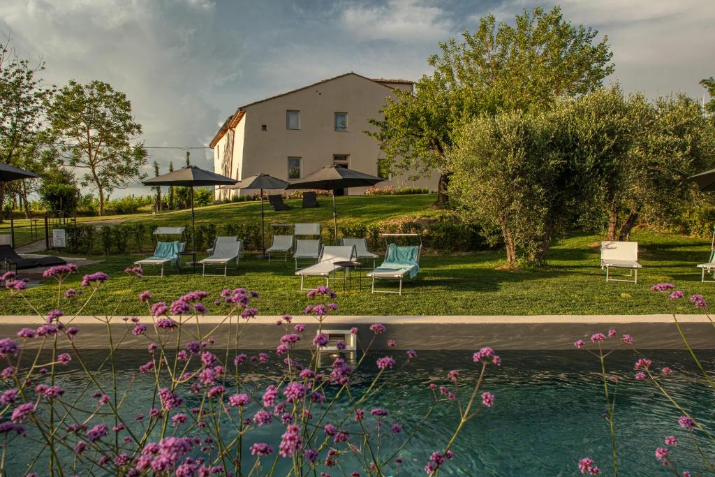 a building with chairs and a pool and flowers at Borgo Elissa Country Relais in Certaldo