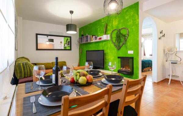 comedor con mesa y pared verde en Casa Jaime, en Monachil