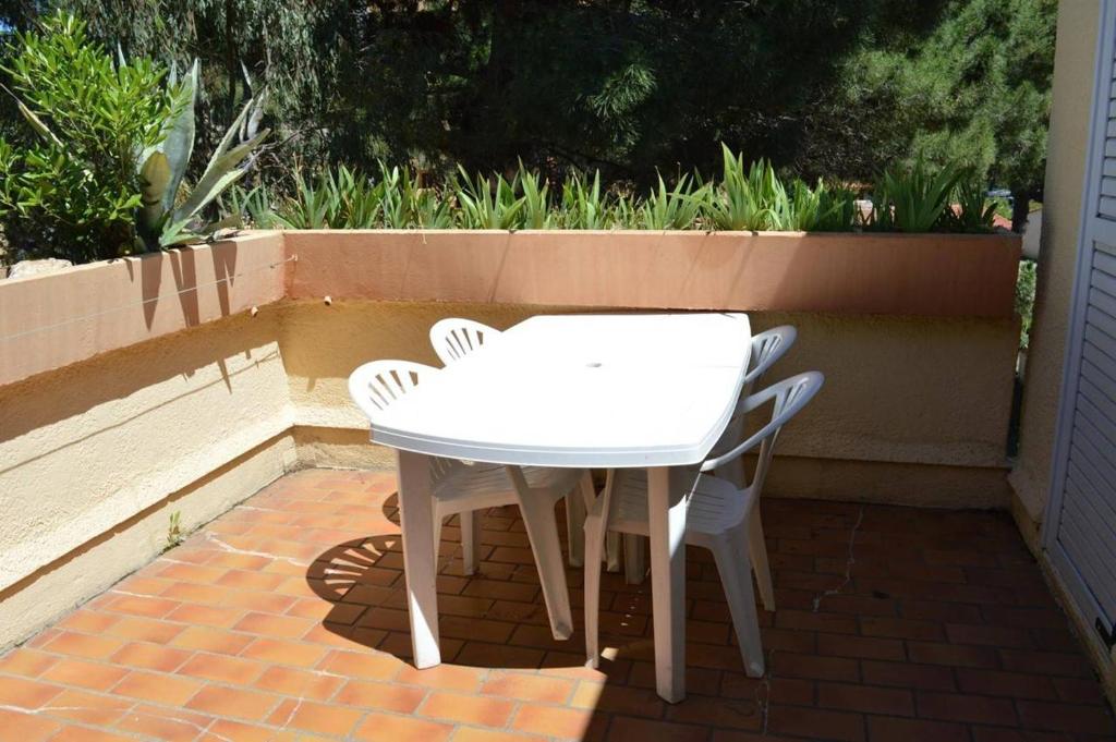 une table et des chaises blanches sur une terrasse en briques dans l'établissement Appartement 2 pièces 4 couchages ARGELES SUR MER AR450-1721, à Argelès-sur-Mer