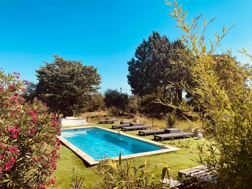 a swimming pool in a yard with benches and trees at Bastide provençale avec piscine in Cotignac
