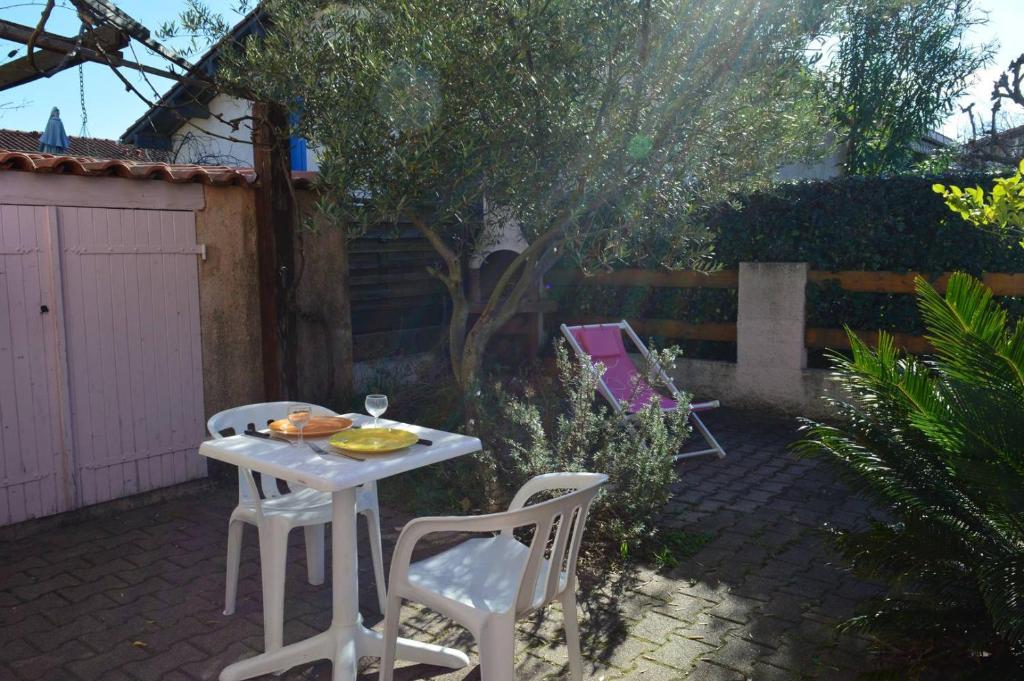 une table blanche et deux chaises dans une cour arrière dans l'établissement Maison 2 pièces mezzanine 4 couchages ARGELES SUR MER AR150-069, à Argelès-sur-Mer