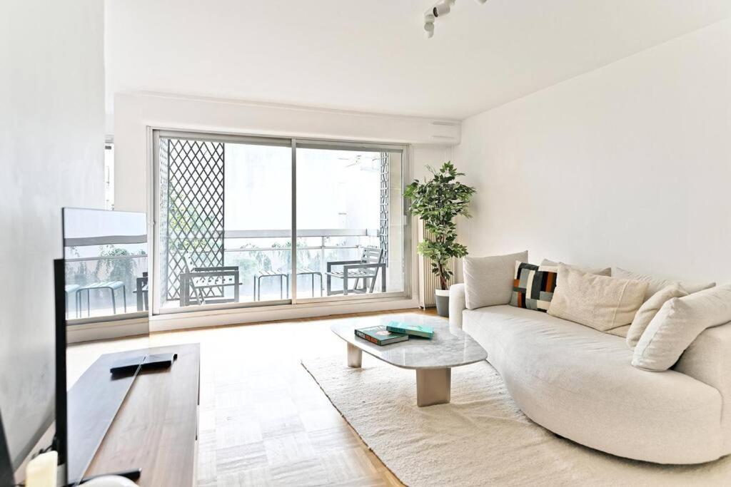 un salon blanc avec un canapé et une table dans l'établissement Appartement Spacieux avec Balcon Le Bon marché, à Paris