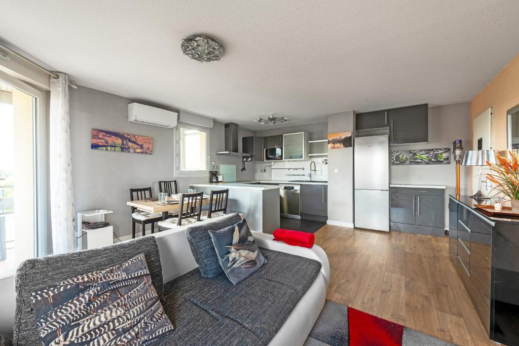 un salon avec un canapé et une cuisine dans l'établissement T3 - 2 places de parking - balcon - Climatisation, à Toulouse