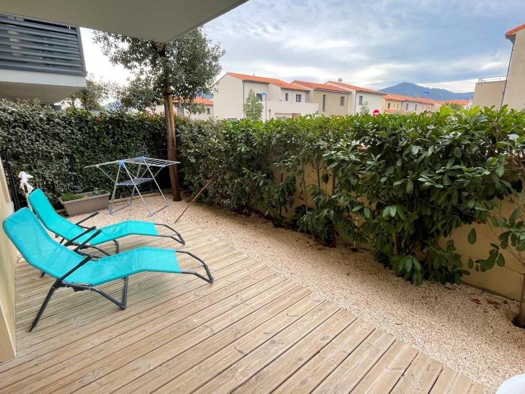 une chaise bleue assise sur une terrasse devant une haie dans l'établissement Appartement 3 pièces 6 personnes- ARGELES VILLAGE AR140-003, à Argelès-sur-Mer