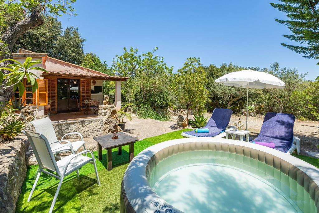 a backyard with a pool with chairs and an umbrella at La salve d´en Jordi in Pollença