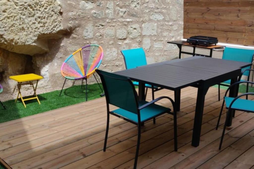 une table et des chaises noires sur une terrasse en bois dans l'établissement Gîte à Saint-Sauveur, à Saint-Sauveur