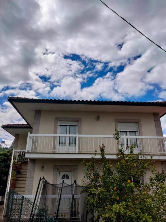 a white house with a balcony and a cloudy sky at La Casa de Marta in Ribeira de Pena