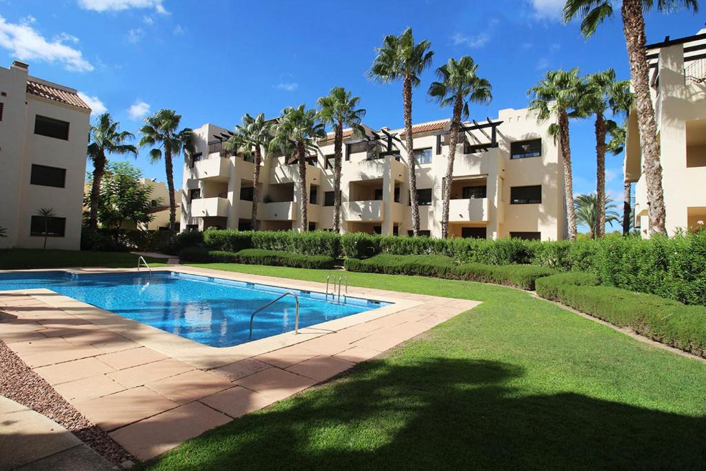 ein großes Apartmenthaus mit einem Pool und Palmen in der Unterkunft Two Bedroom Penthouse Apartment In Roda Golf in Los Cortados