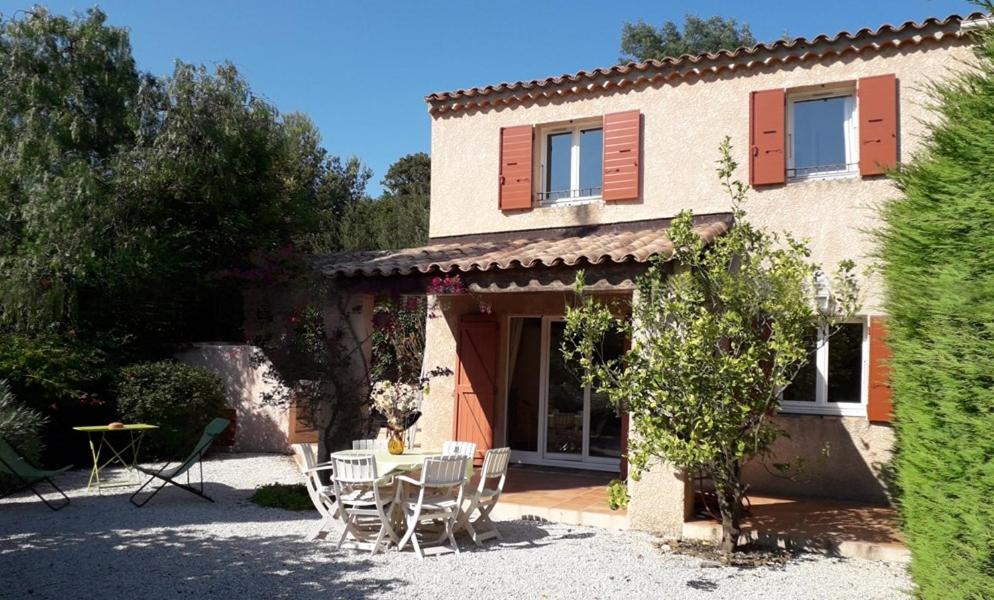 une maison avec des chaises et une table devant elle dans l'établissement VILLA 2 CHAMBRES dans RESIDENCE avec PISCINE, à Cavalaire-sur-Mer
