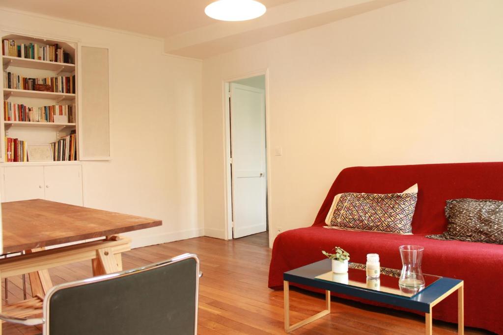 un salon avec un canapé rouge et une table dans l'établissement Appartement dans le Marais, à Paris