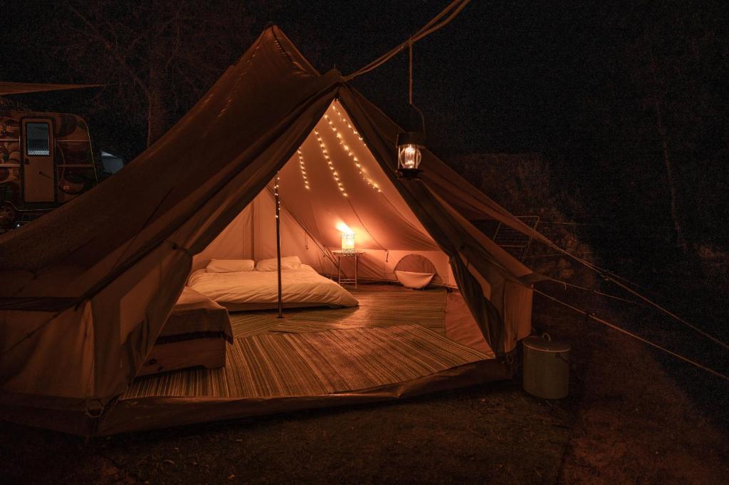 a tent with a bed and lights in the dark at Slow Life Camping Venta del Moro in Venta del Moro