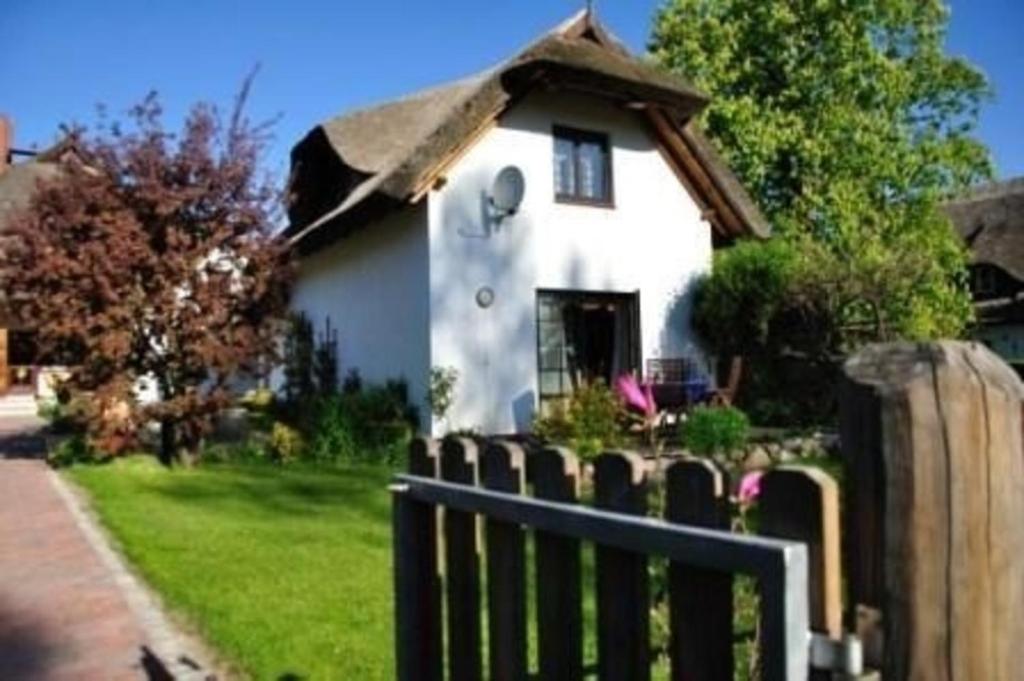 a white house with a thatched roof behind a fence at Schönes Ferienhaus in Althagen mit Terrasse und Grill in Ahrenshoop