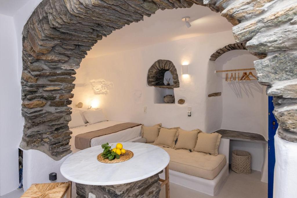 a living room with a table and a stone wall at Adamma Tinos in Kékhros