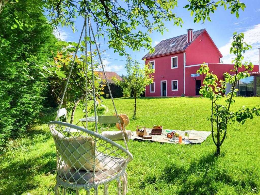 une balançoire dans une cour devant une maison rouge dans l'établissement AG Casa Bértoa con jardín y comedor exterior x8, à Queo de Abaixo