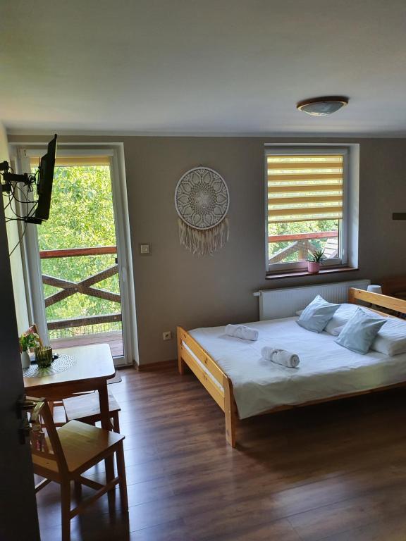 a bedroom with a bed and a table and a window at Sieraton Pokoje i Apartament in Stronie Śląskie
