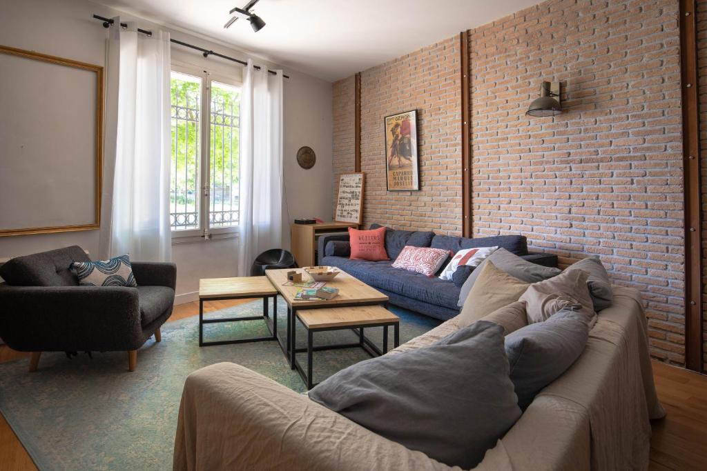un salon avec un canapé et un mur de briques dans l'établissement Workshop, à Béziers
