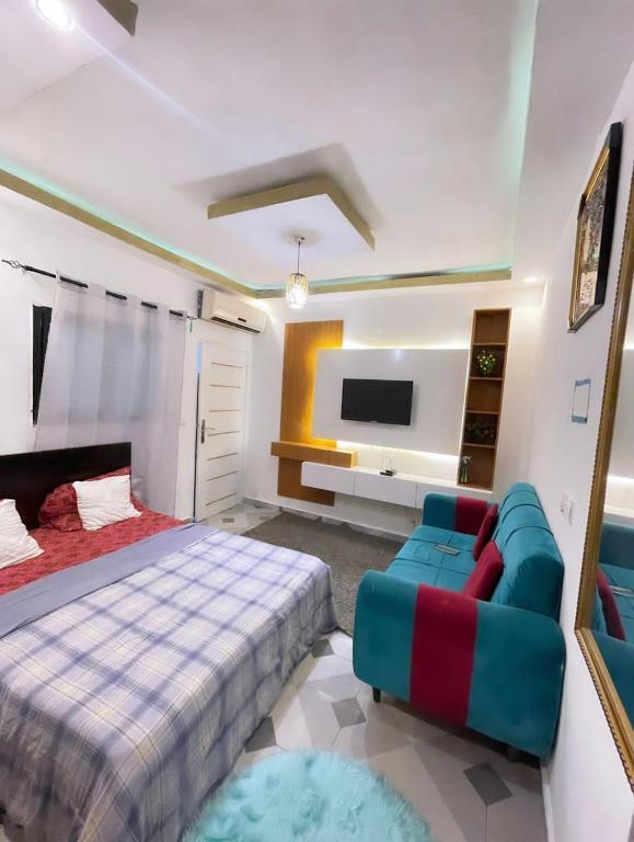 ein Schlafzimmer mit einem Bett, einer Couch und einem Fernseher in der Unterkunft Résidence in Abidjan