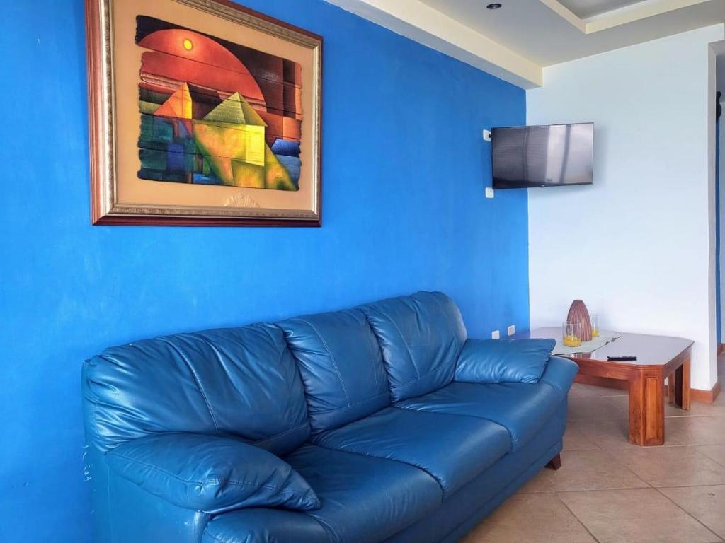 a blue couch in a living room with a painting at Departamento mirador al mar in Tonsupa