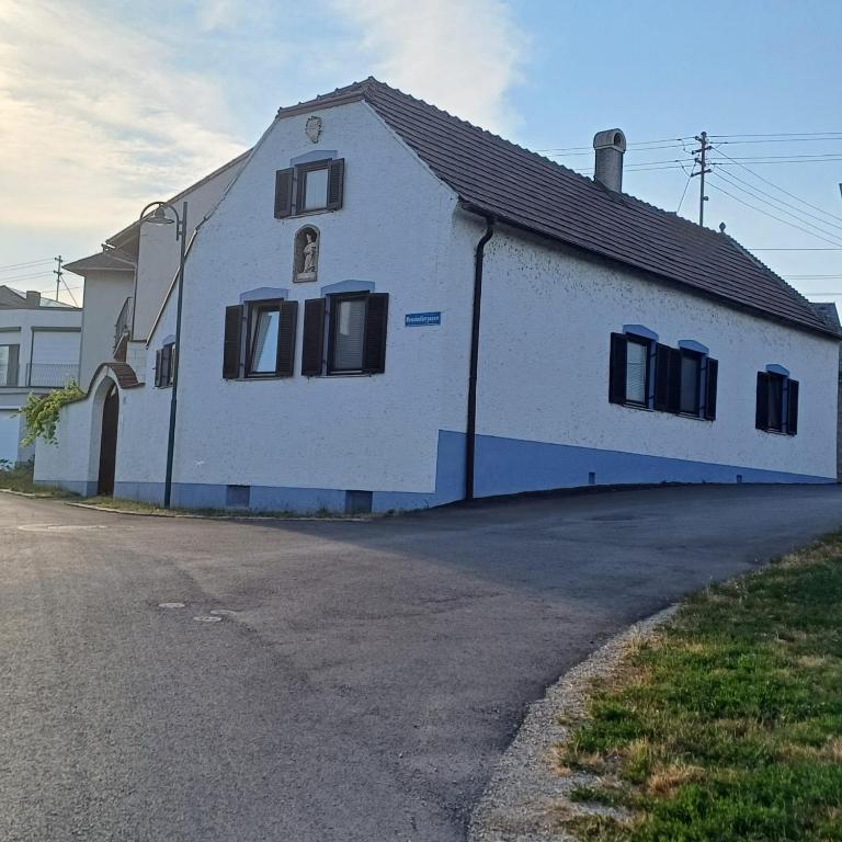 a white building with black windows on a street at Urbanihof in Jois in Jois
