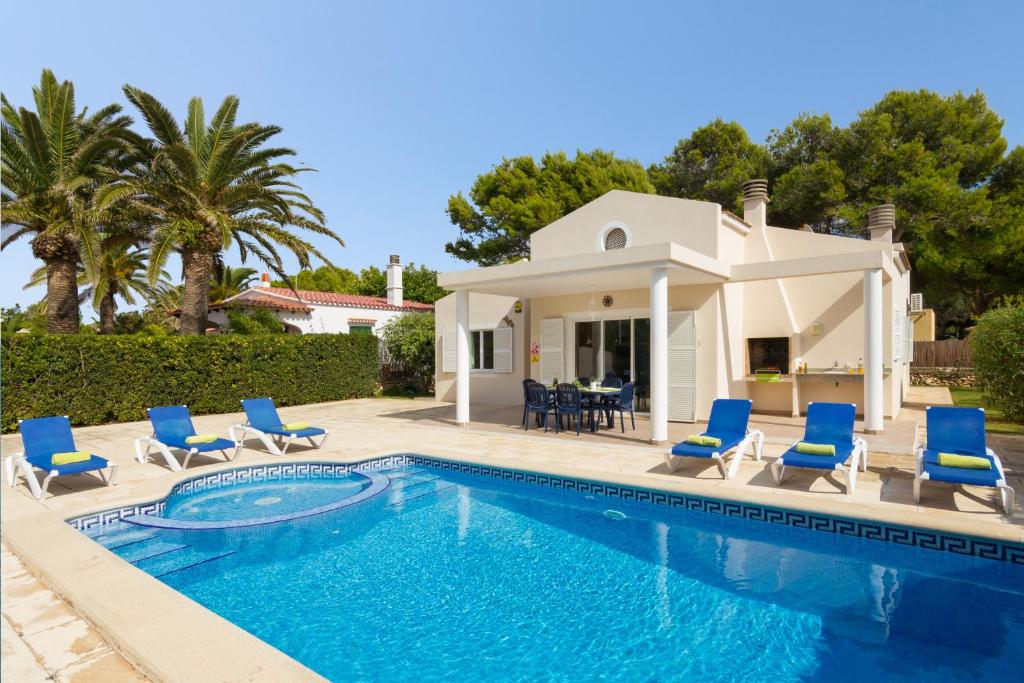 a villa with a swimming pool and blue chairs at Villa Roser in Ciutadella