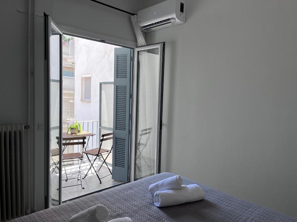 a bedroom with a bed and a balcony with a table at Miranda's Apartment Koukaki in Athens