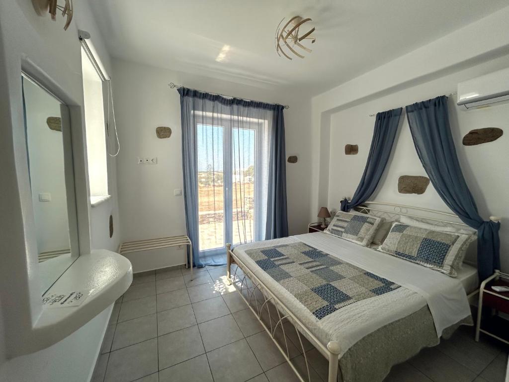 a bedroom with a bed with blue curtains and a window at Antiparos Diamond in Antiparos Town