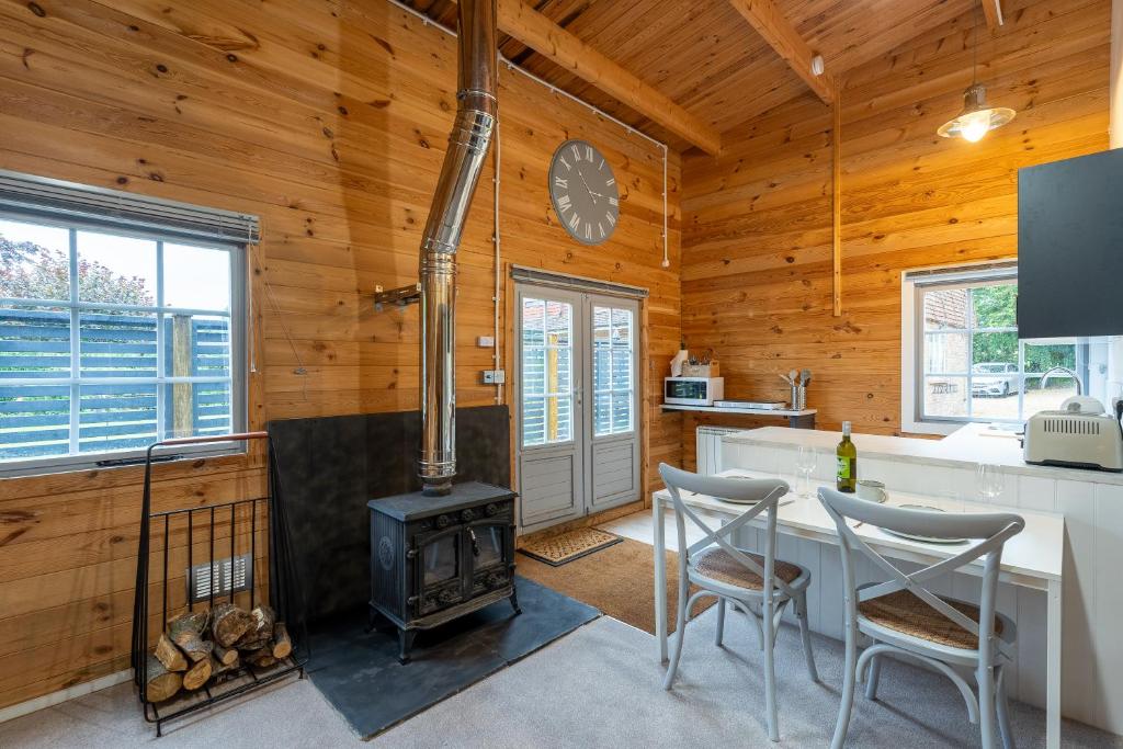 a kitchen with a stove in a wooden cabin at Walliswood Lodge - Wood Burner, Air Con & Wi-fi, Rural Retreat in Ewhurst