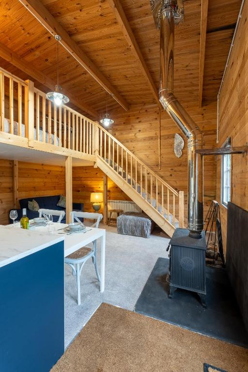 a living room with a fireplace in a wooden house at Walliswood Lodge - Wood Burner, Air Con & Wi-fi, Rural Retreat in Ewhurst