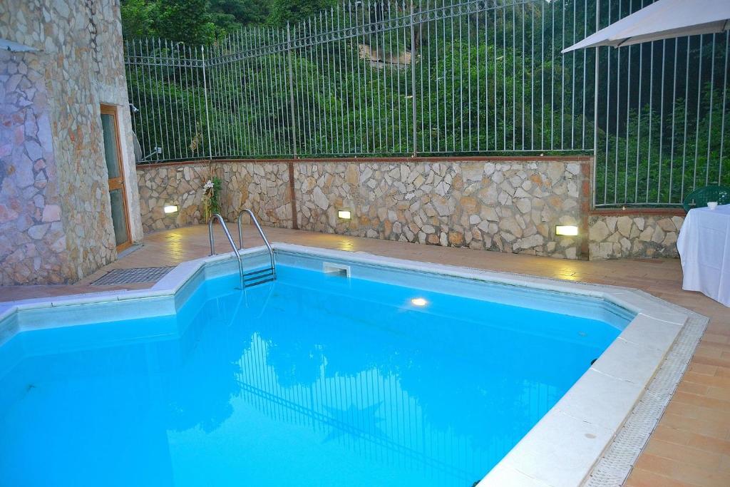 a swimming pool with a stone wall and a fence at Giardini Di Capodimonte Apartment in Naples