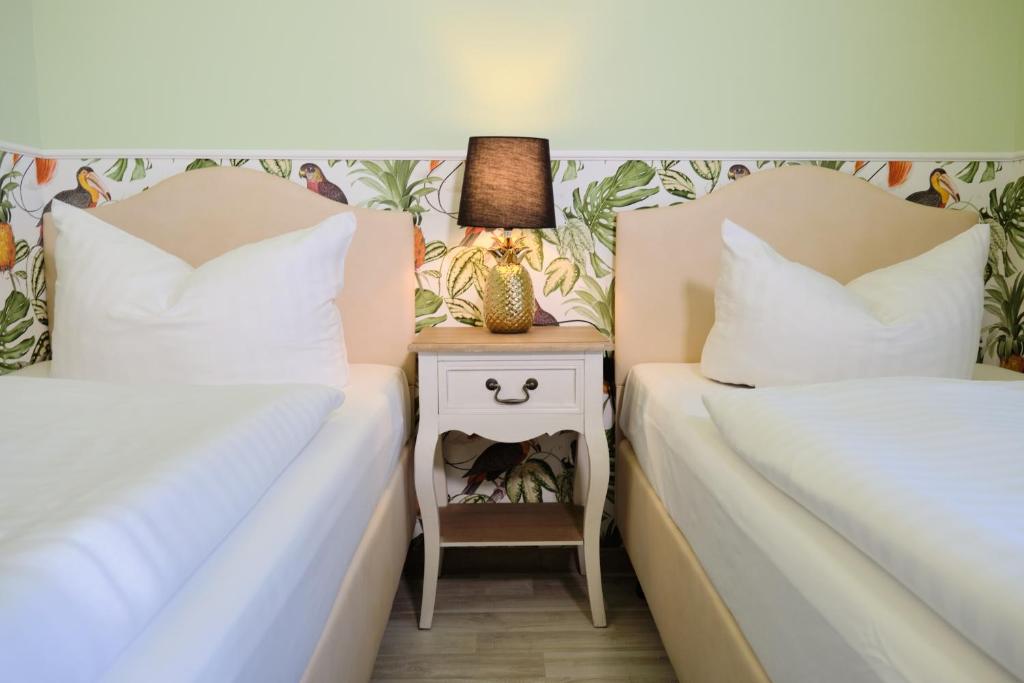 two beds next to each other with a nightstand between them at Anno 1900 Hotel Babelsberg in Potsdam
